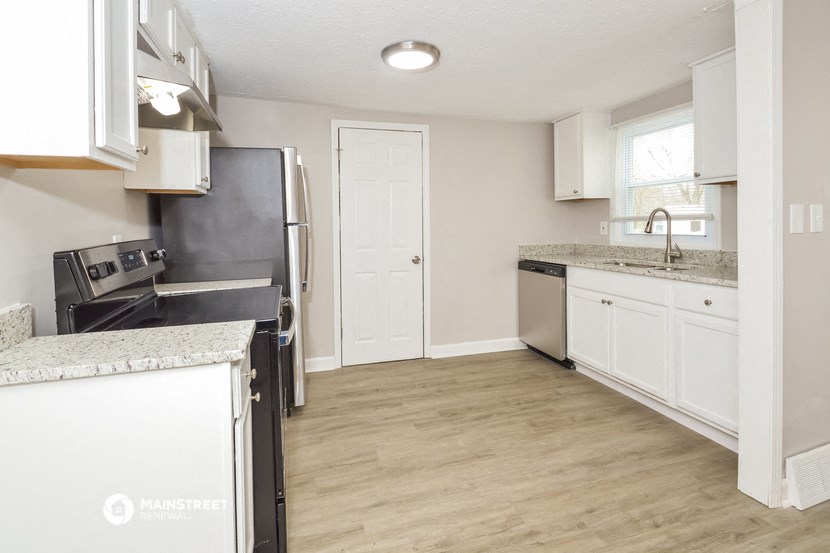 an empty kitchen with white cabinets and a black refrigerator