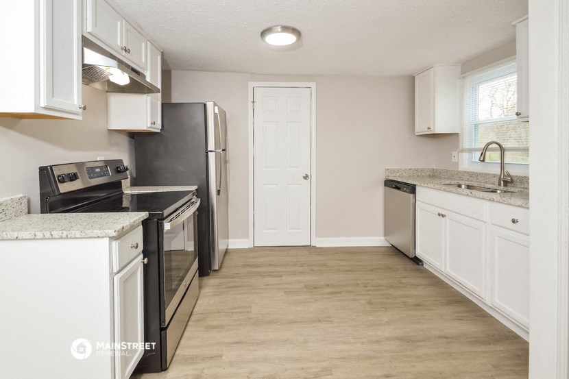 a kitchen with white cabinets and black appliances and a refrigerator