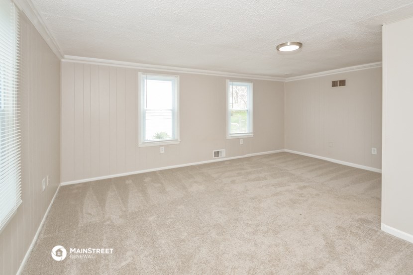 the spacious living room with carpeting and windows