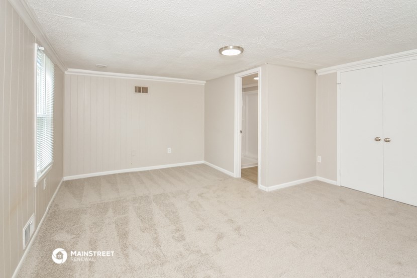a spacious living room with carpet and a door to a closet