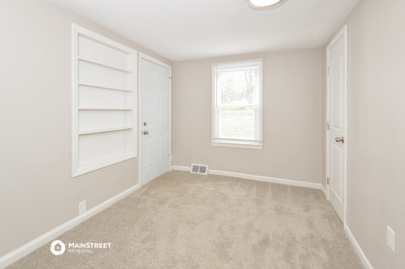 a bedroom with a closet and a window and a carpeted floor