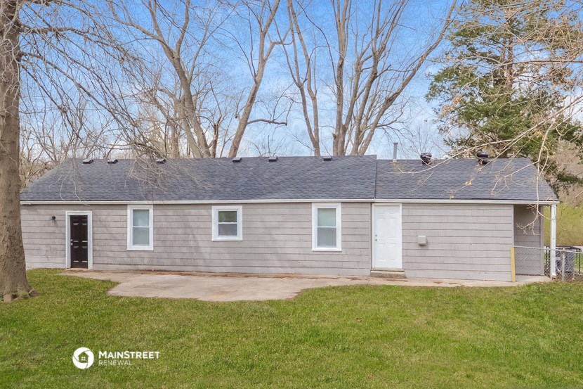 a small gray house with trees in the background