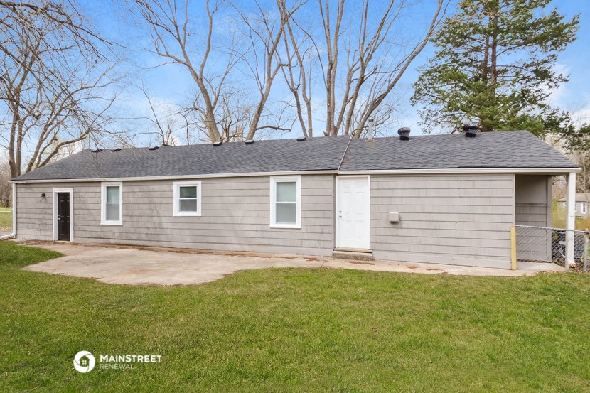 the front of a gray house with a driveway and grass