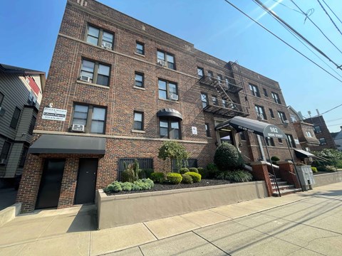 A brick building with a black awning and a sign that reads "322" is in front of a clear blue sky.