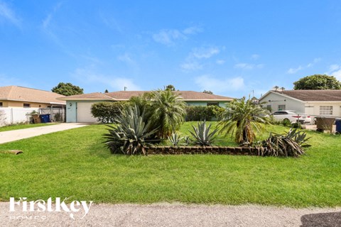 a yard with palm trees in front of a house