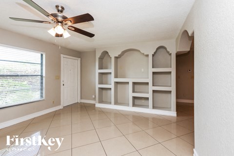 a dining room with white shelves and a ceiling fan