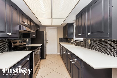 a kitchen with black cabinets and white counters and a door