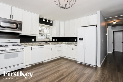 A modern kitchen with white cabinets and a wooden floor.