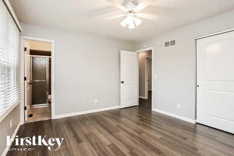 A spacious room with a ceiling fan and wooden flooring.