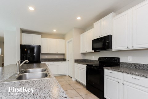 a kitchen with white cabinets and black appliances and granite counter tops
