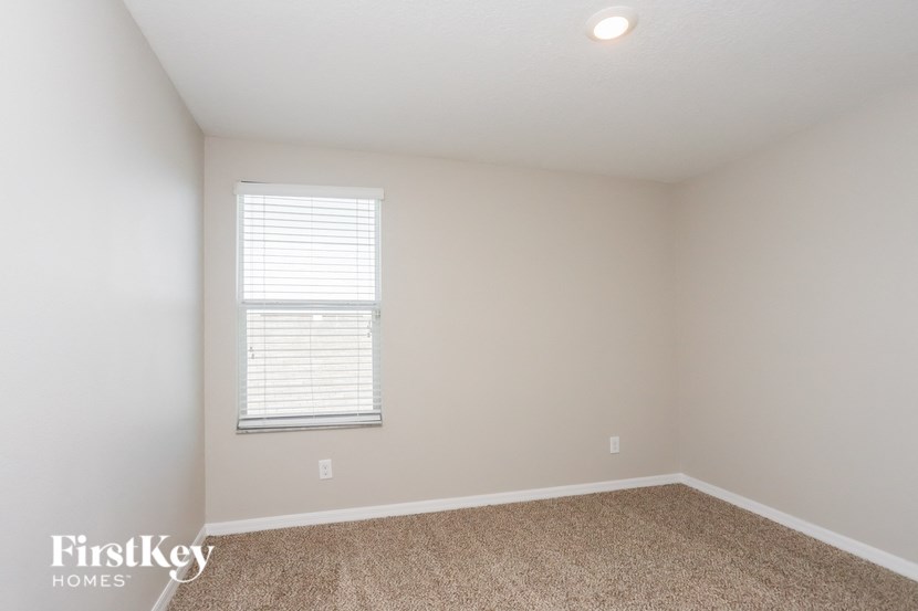 a bedroom with white walls and a window and carpet