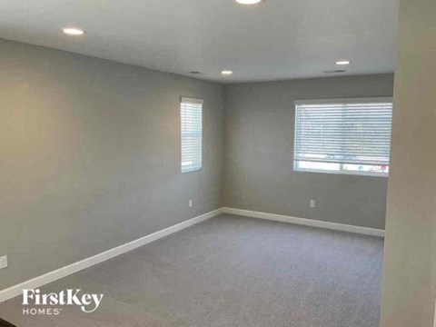 an empty living room with a window and gray walls