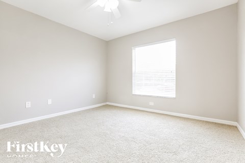a bedroom with white carpet and a large window