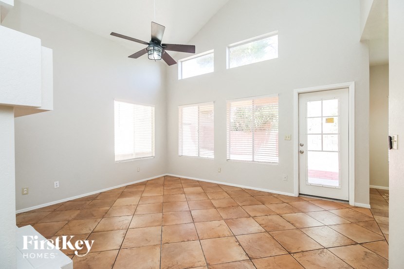 an empty living room with a ceiling fan and windows