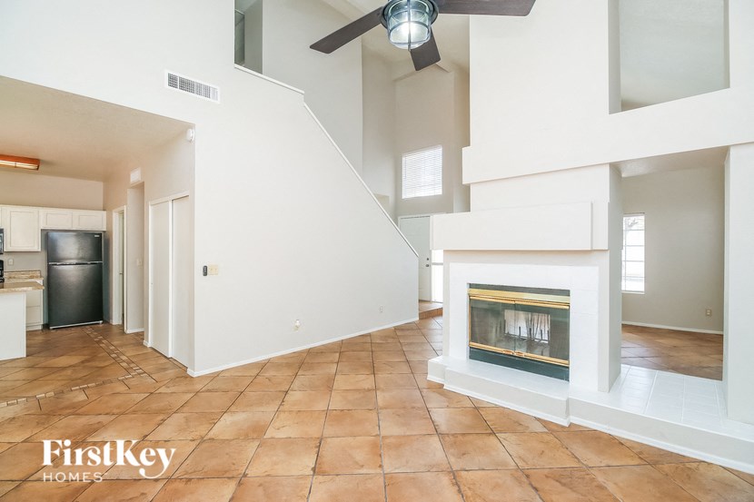 a large living room with a fireplace and a ceiling fan