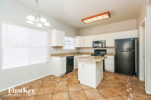 a kitchen with an island and a black refrigerator