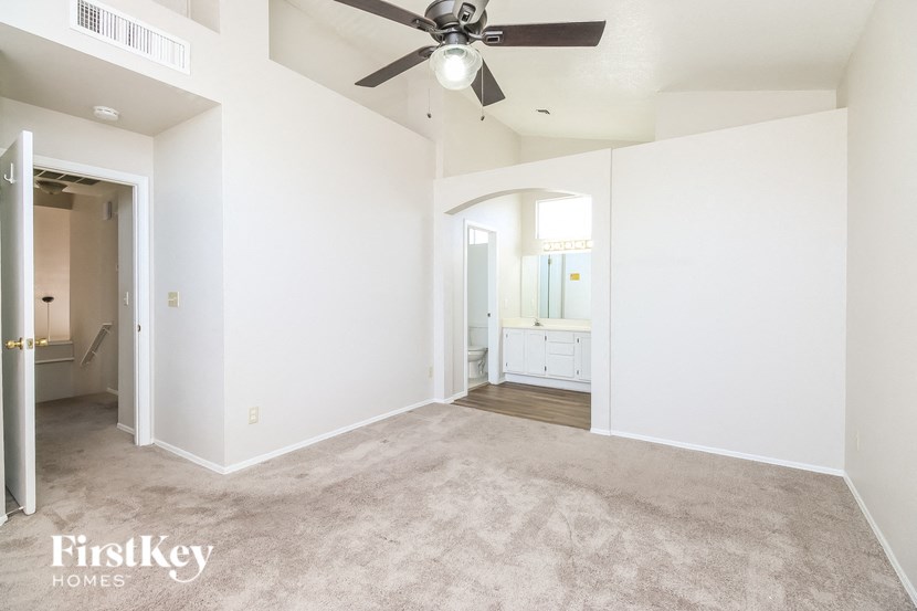 an empty living room with a ceiling fan and white walls