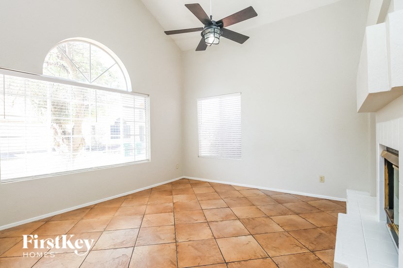 an empty living room with a ceiling fan and a large window