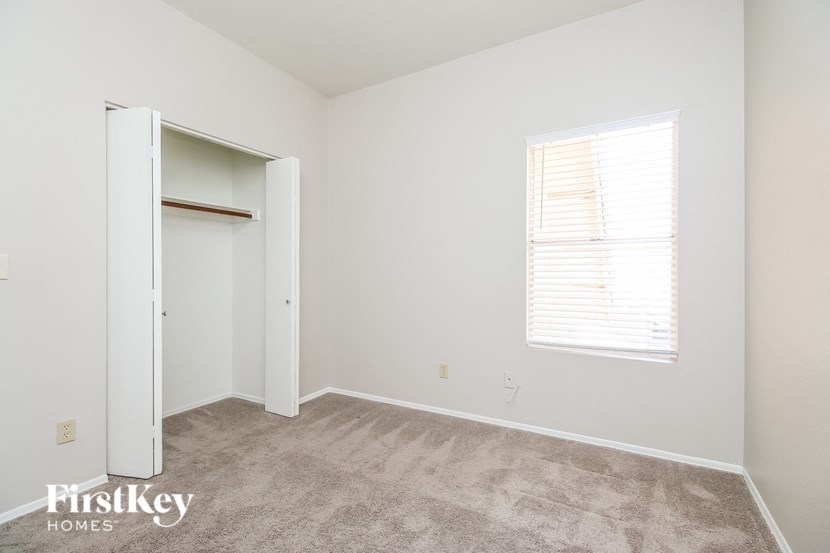 a bedroom with a closet and a window and a carpeted floor