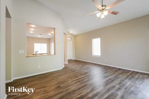 A spacious room with wooden floors and a ceiling fan.