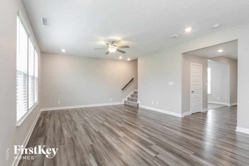 A spacious room with wooden flooring and a ceiling fan.