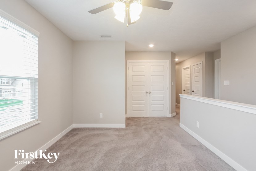 A spacious room with a ceiling fan and a window with blinds.