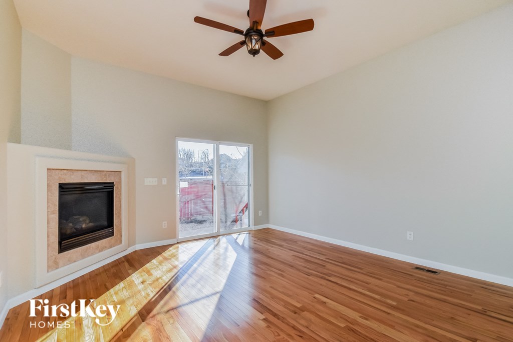 an empty living room with a fireplace and a ceiling fan