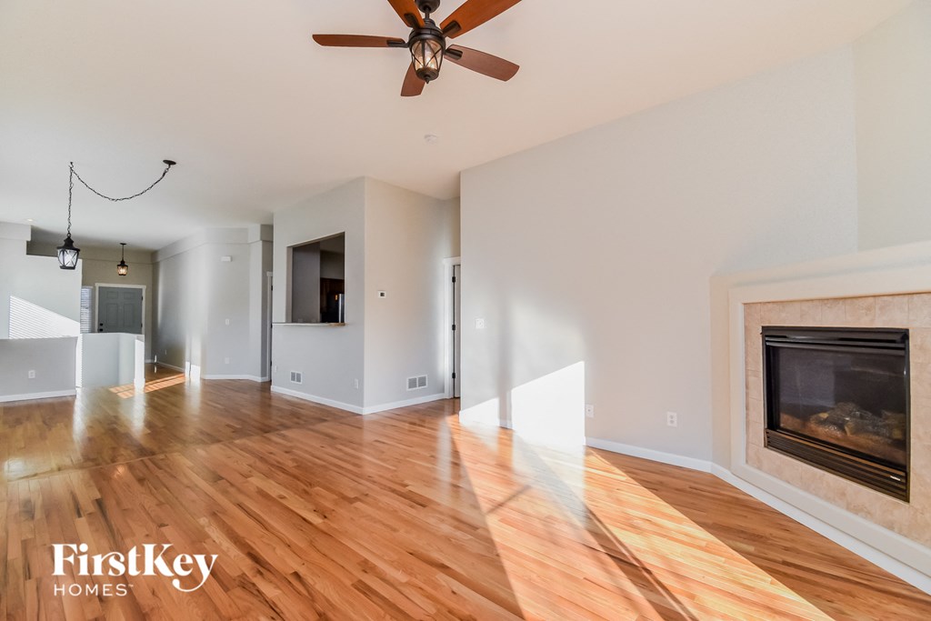 an empty living room with a fireplace and wooden floors