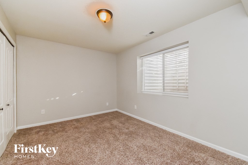 the spacious bedroom with carpeted flooring and a large window