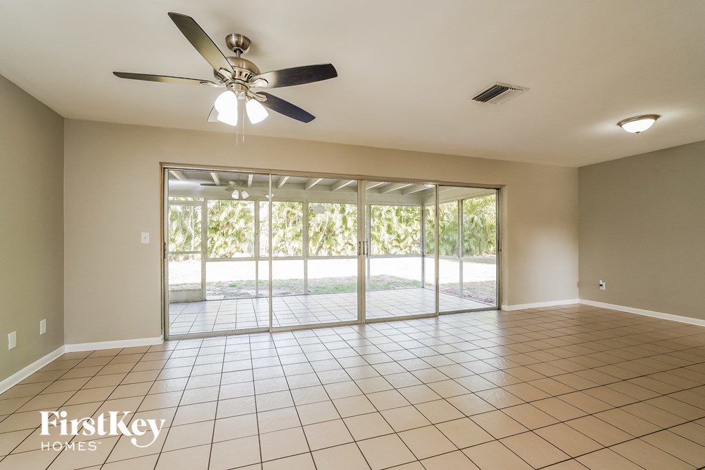 A spacious room with a ceiling fan and sliding glass doors leading to a patio.