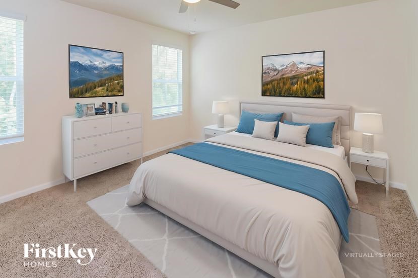 A bedroom with a large bed, a dresser, and two pictures on the wall.