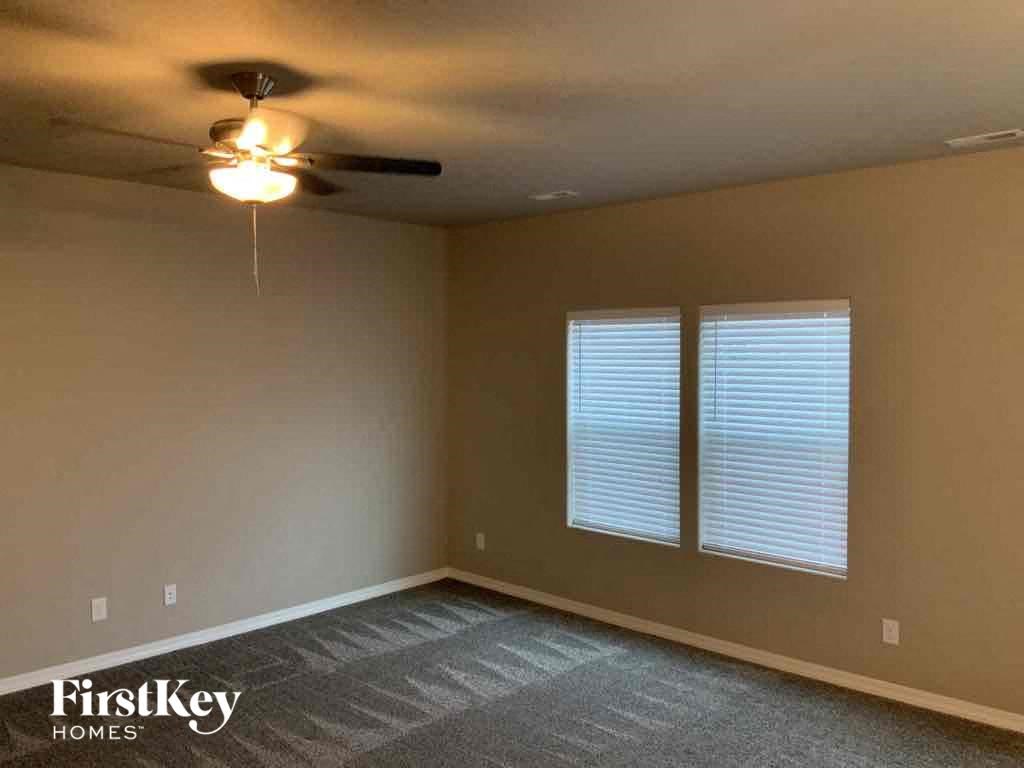 A room with a ceiling fan and two windows.