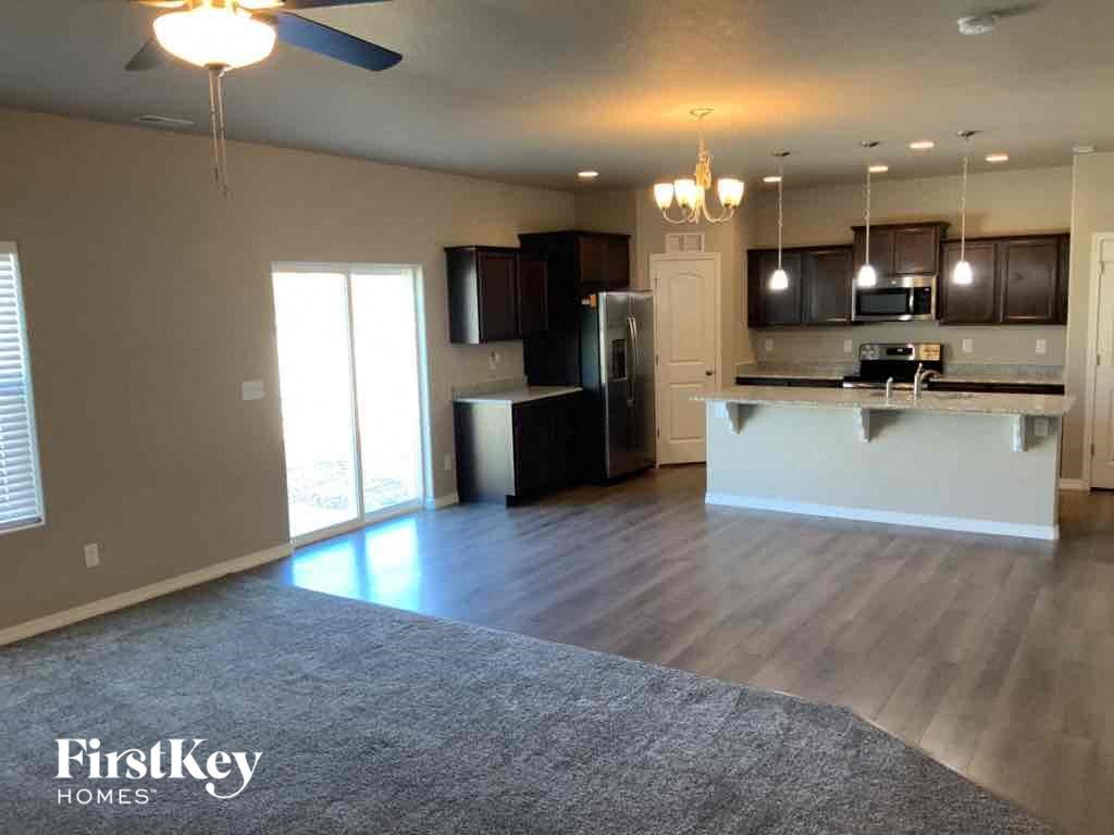 A spacious kitchen and living room with a grey rug on the floor.