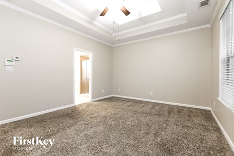 A spacious room with a carpeted floor and a ceiling fan.