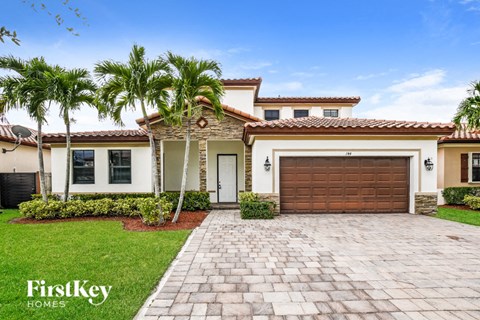 a house with a garage door and palm trees