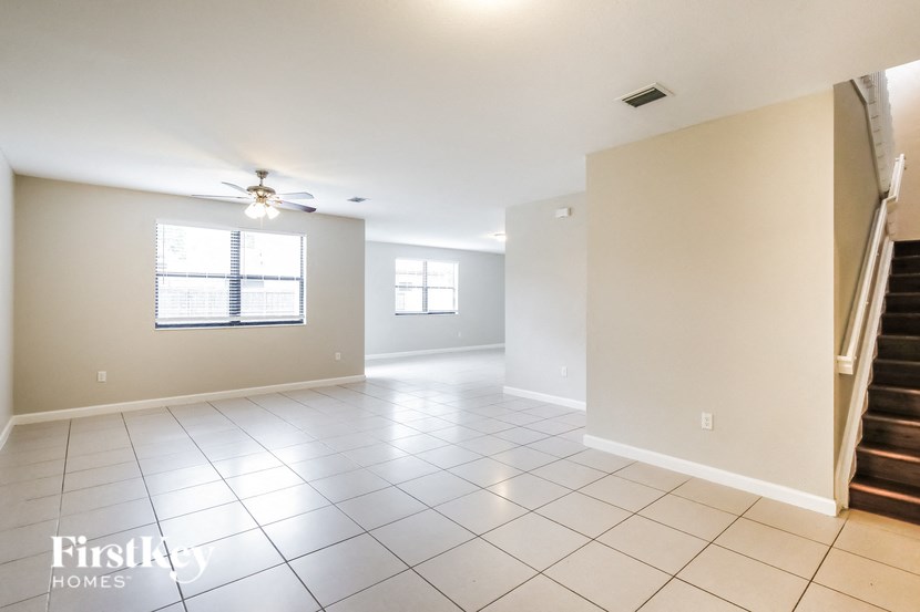 a empty living room with a ceiling fan and a staircase