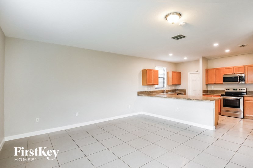 an empty kitchen and living room with white tile flooring
