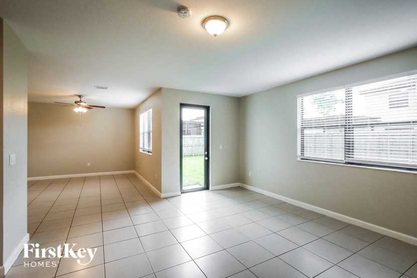 an empty living room with a ceiling fan and a window