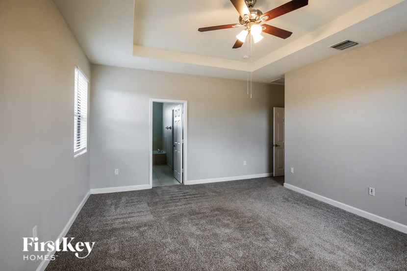 an empty living room with a ceiling fan and a closet