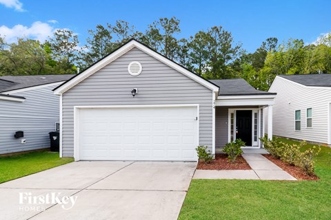 A grey house with a white garage door and a small garden in front.