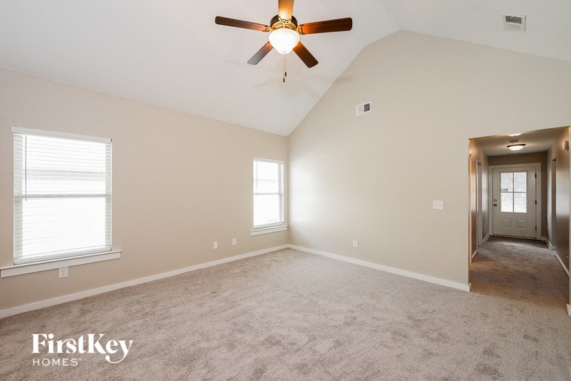 A spacious room with a ceiling fan and two windows.