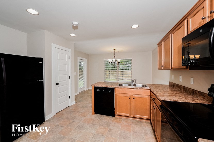 A kitchen with a black fridge and wooden cabinets.