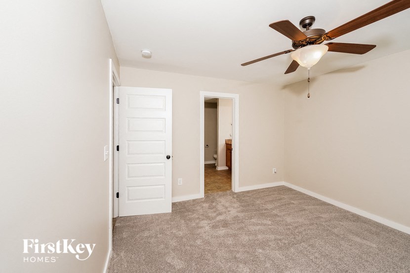 A spacious room with a ceiling fan and two doors.