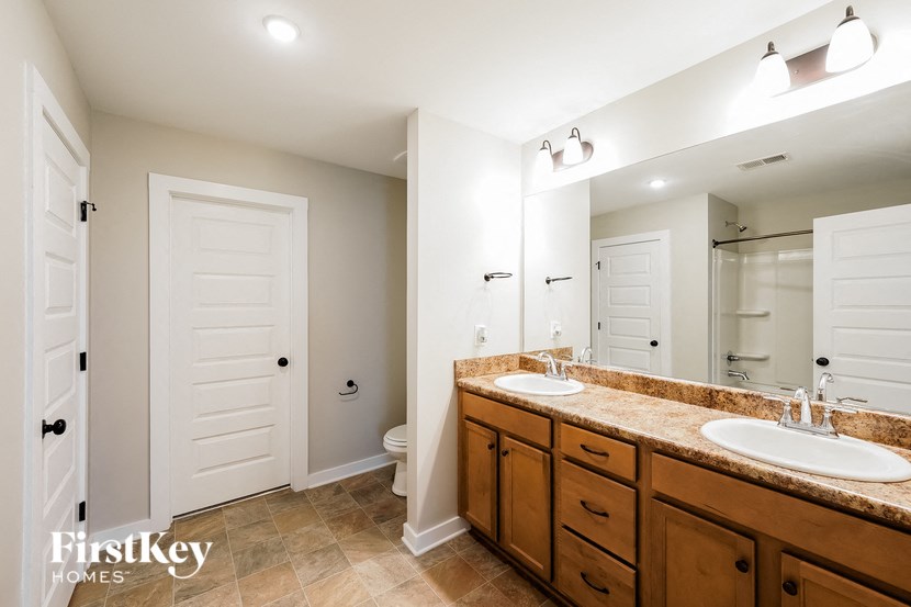 A bathroom with a toilet, sink, and mirror.