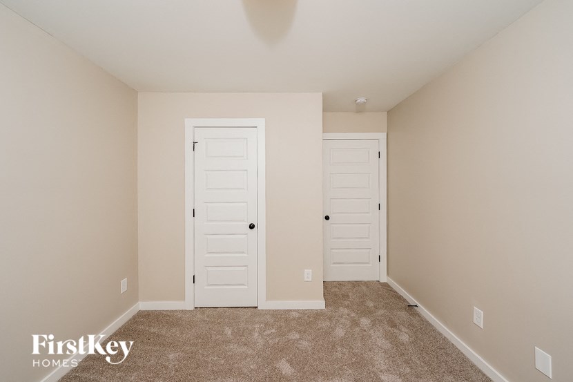 A room with two white doors and a carpeted floor.