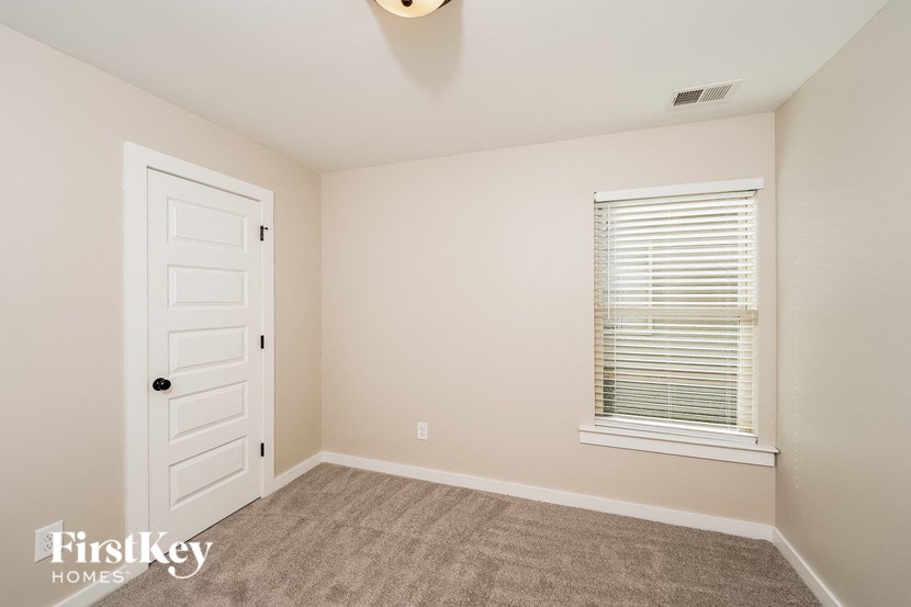 A room with a white door and a window with blinds.