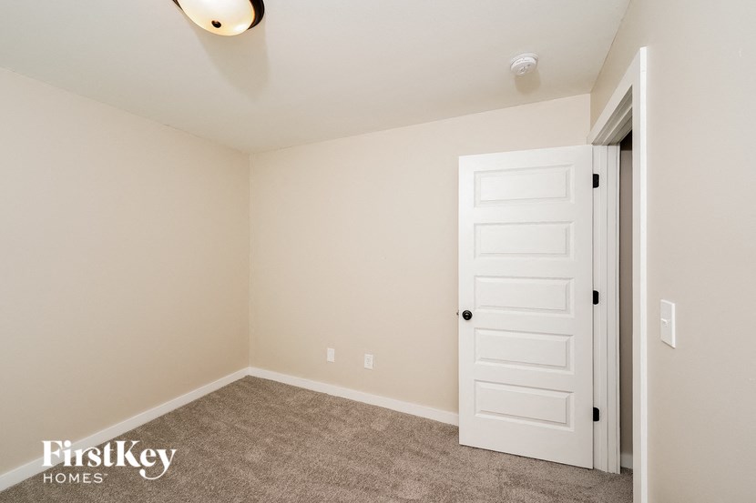 A room with a white door and a carpeted floor.
