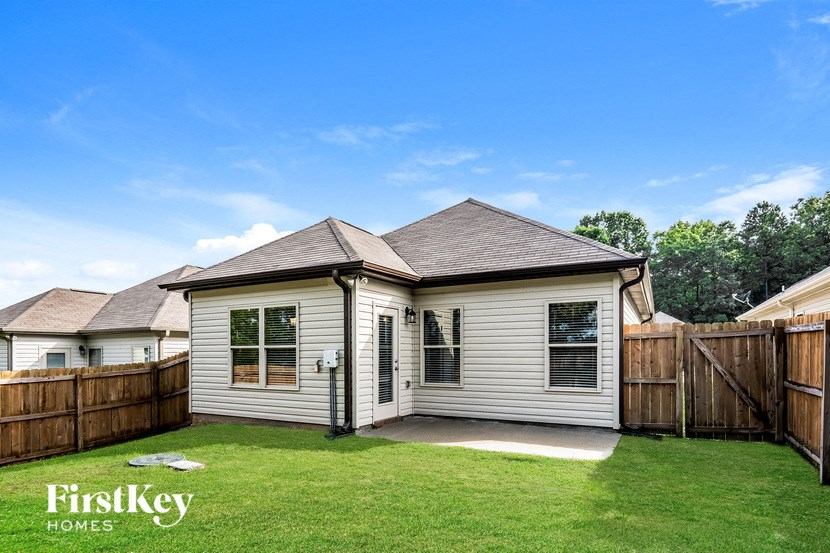 A house with a brown roof and a white exterior is surrounded by a wooden fence.