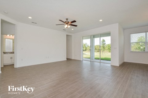 A spacious room with a ceiling fan and sliding glass doors.