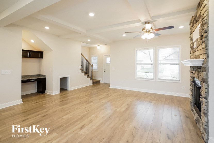 an empty living room with a fireplace and a ceiling fan